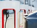 Elektroauto lädt an mehreren Tesla Supercharger-Schnellladestationen in einer Reihe.