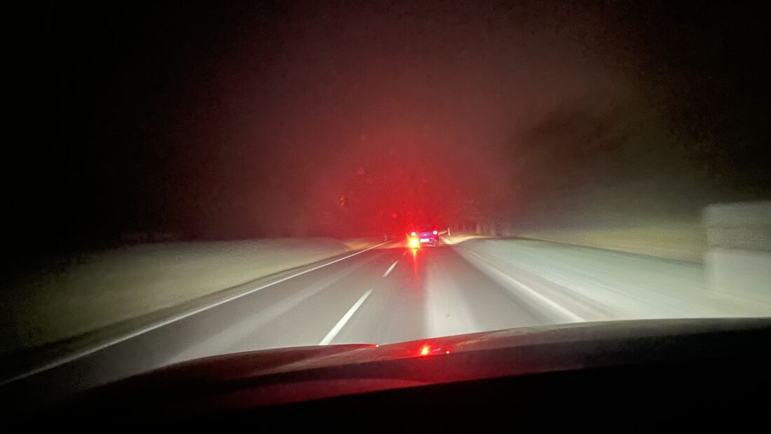 Fahrzeug mit eingeschalteter Nebelschlussleuchte bei Nacht auf Landstraße, Rücklicht blendet nachfolgende Verkehrsteilnehmer bei eingeschränkter Sicht.