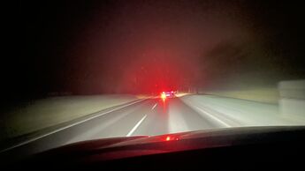 Fahrzeug mit eingeschalteter Nebelschlussleuchte bei Nacht auf Landstraße, Rücklicht blendet nachfolgende Verkehrsteilnehmer bei eingeschränkter Sicht.
