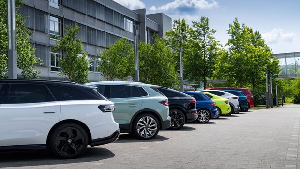 Fahrzeuge der Volkswagen Gruppe stehen auf einem Parkplatz vor einem Unternehmensgebäude.