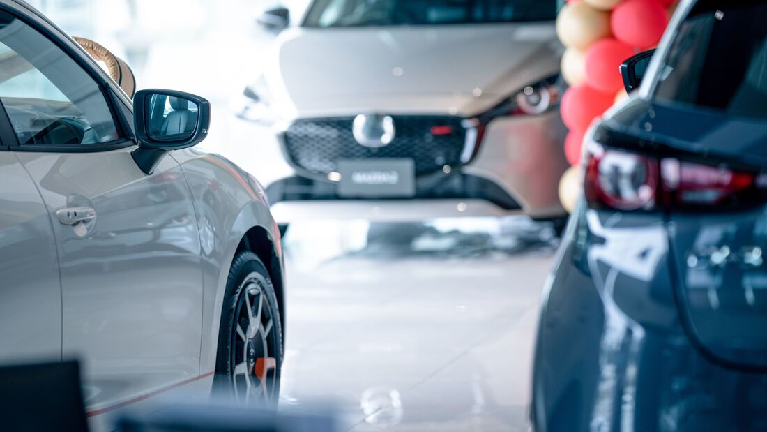 Fahrzeuge in einem Autohaus mit Fokus auf mehreren Modellen im Ausstellungsraum, Symbol für Auswahl und Leasingangebote.
