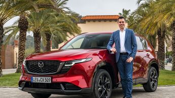Felix Gebhart, Vertriebschef von Mazda Deutschland, steht neben einem roten Mazda CX-5 im Außenbereich.