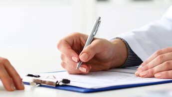Female doctor hand hold silver pen filling patient history list