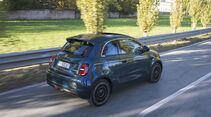 Fiat 500 Hybrid bei der Fahrt auf einer Landstraße aus der Heckperspektive.