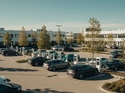 Firmenparkplatz mit mehreren Elektroautos an Ladesaeulen vor Buerogebaeuden