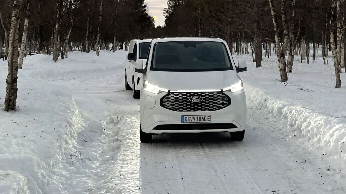 Ford E-Transit Custom beim Wintertest auf schneebedeckter Straße, Frontansicht des Fahrzeugs im Testbetrieb.