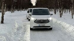 Ford E-Transit Custom beim Wintertest auf schneebedeckter Straße, Frontansicht des Fahrzeugs im Testbetrieb.