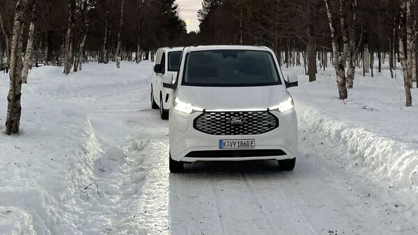Ford E-Transit Custom beim Wintertest auf schneebedeckter Straße, Frontansicht des Fahrzeugs im Testbetrieb.