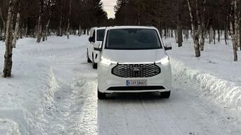 Ford E-Transit Custom beim Wintertest auf schneebedeckter Straße, Frontansicht des Fahrzeugs im Testbetrieb.