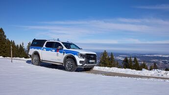 Ford Ranger Plug-in-Hybrid mit Einsatzkennzeichnung im Schnee auf einer Bergstraße in den Alpen.