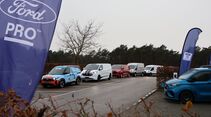 Ford Transit und Transit Custom als Fahrzeugreihe beim Ford Pro Leisure Experience Event in Lommel, mit Ford Pro Flaggen am Parkplatz.