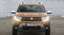Frontalansicht eines stehenden Dacia Duster der zweiten Generation mit eingeschalteter Beleuchtung.
