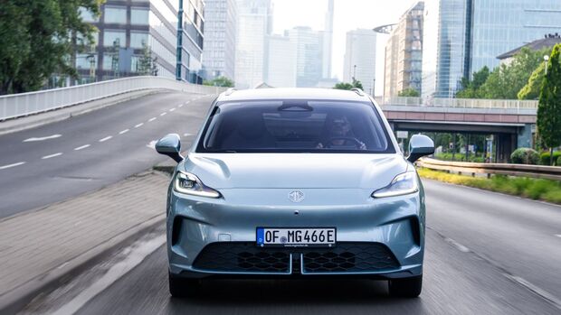 Frontansicht des hellblauen MG4 EV Urban Luxury während der Fahrt auf einer Straße in der Stadt.