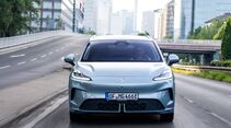 Frontansicht des hellblauen MG4 EV Urban Luxury während der Fahrt auf einer Straße in der Stadt.