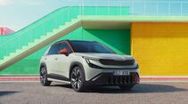 Frontansicht des Škoda Epiq Elektro-SUV vor einem farbigen Gebäude mit grüner Treppe und gelber Wand.