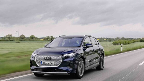 Frontansicht eines Audi Q4 e-tron während der Fahrt auf Landstraße mit geschlossenem Kühlergrill.