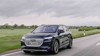 Frontansicht eines Audi Q4 e-tron während der Fahrt auf Landstraße mit geschlossenem Kühlergrill.