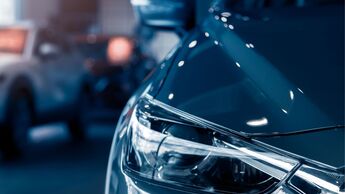 Frontpartie eines Neuwagens in einer Fahrzeughalle, Fokus auf Scheinwerfer und Karosserie