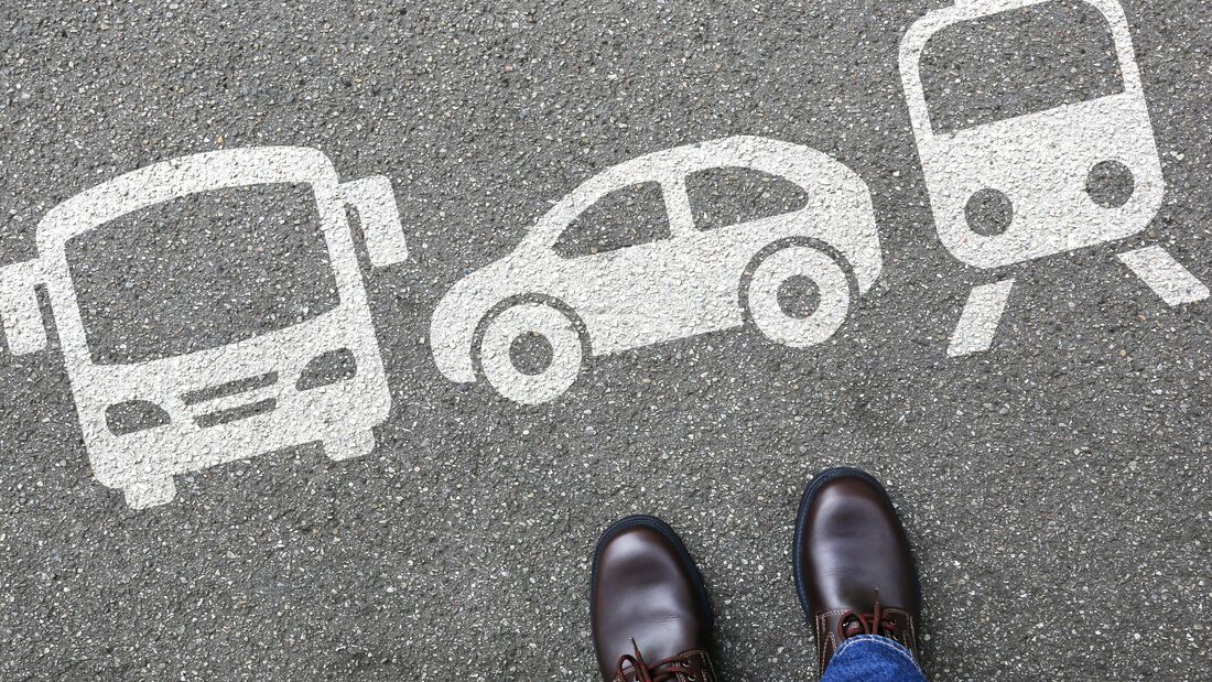 Füße auf Asphalt vor Symbolen für Bus, Auto und Zug als Darstellung verschiedener Verkehrsmitteloptionen.