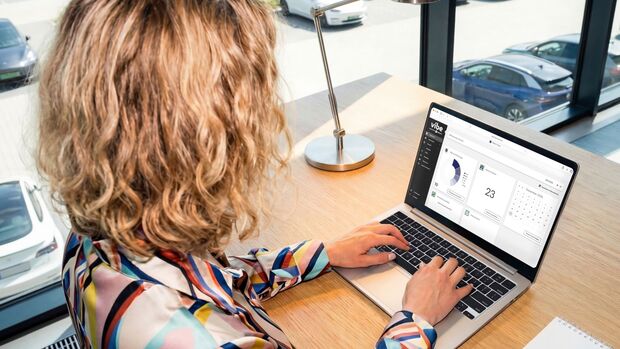 Fuhrparkmanager arbeitet am Laptop mit Fleet-Cockpit-Software zur Übersicht von Dienstwagen-Fahrzeugdaten einer Elektroauto-Flotte.