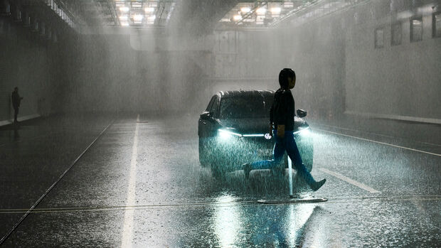 Fußgänger-Dummy überquert bei starkem Regen die Fahrbahn vor einem Fahrzeug in einer ADAC-Testhalle