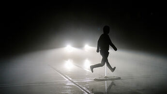 Fußgänger-Dummy vor einem Fahrzeug mit eingeschalteten Scheinwerfern in dichter Nebelumgebung während eines ADAC-Tests