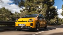 Gelber Renault Twingo E-Tech Electric bei der Fahrt auf einer Straße, schräg von vorn aufgenommen.