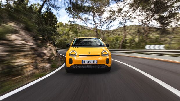 Gelber Renault Twingo E-Tech Electric in Frontansicht bei der Fahrt durch eine Kurve auf einer Landstraße.