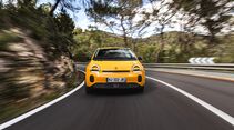 Gelber Renault Twingo E-Tech Electric in Frontansicht bei der Fahrt durch eine Kurve auf einer Landstraße.