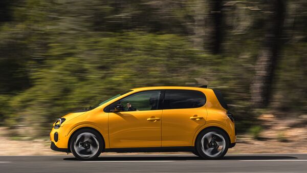 Gelber Renault Twingo E-Tech Electric in Seitenansicht während der Fahrt auf einer Straße.