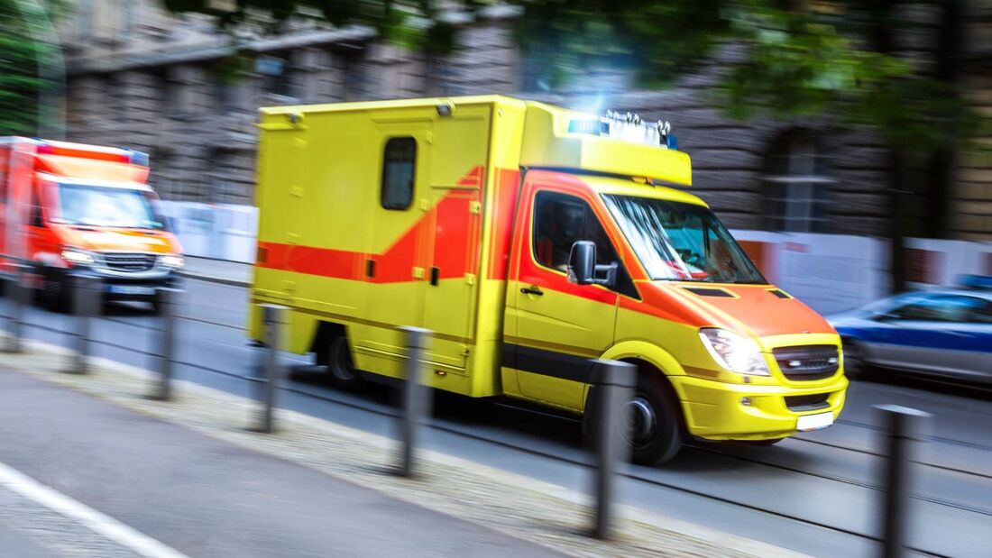Gelber Rettungswagen mit Blaulicht fährt auf Straße im Stadtverkehr