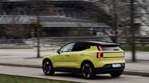 Gelber Volvo EX30 P8 AWD Electric bei einer Fahraufnahme schräg von hinten mit eingeschalteten Rückleuchten.