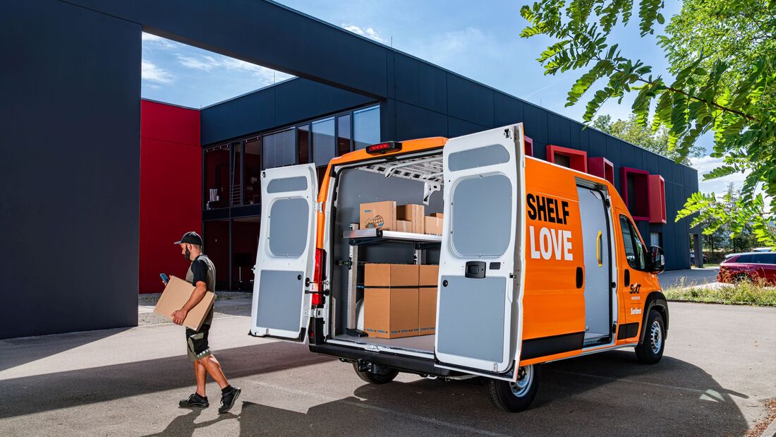 Geöffneter Sixt-van&truck-Transporter mit Sortimo-Regalsystem, ein Zusteller trägt ein Paket zum Fahrzeug.