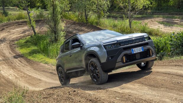 Grüner Jeep Avenger 4xe fährt auf einem unbefestigten Offroad-Parcours über eine Bodenwelle.