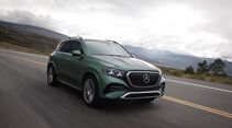Grüner Mercedes-Benz GLE 450e 4MATIC aus schräger Frontperspektive während der Fahrt auf einer Landstraße unter bewölktem Himmel.