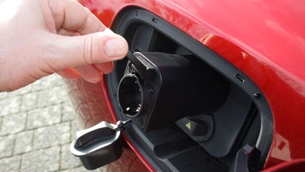 Hand öffnet Ladeanschluss eines Elektroautos mit integriertem V2L-Anschluss