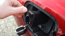 Hand öffnet Ladeanschluss eines Elektroautos mit integriertem V2L-Anschluss