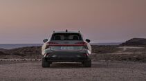 Heckansicht des Audi A6 allroad mit durchgehendem LED-Leuchtenband auf einer Küstenlandschaft.