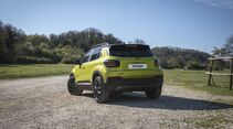 Heckansicht des Jeep Avenger 4xe auf einer Schotterfläche im Freien.