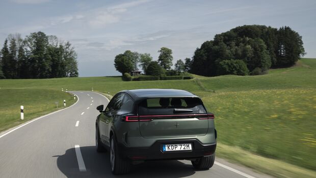 Heckansicht des Polestar 3 Performance während der Fahrt auf einer kurvigen Landstraße.