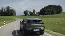 Heckansicht des Polestar 3 Performance während der Fahrt auf einer kurvigen Landstraße.
