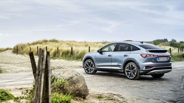 Heckansicht eines Audi Q4 Sportback e-tron auf befestigtem Untergrund mit LED-Rückleuchten.