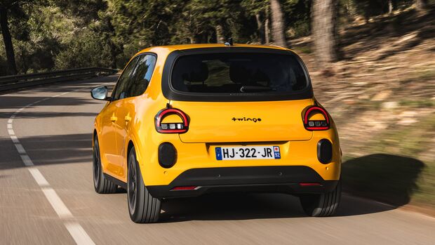Heckansicht eines fahrenden Renault Twingo E-Tech auf einer kurvigen Straße