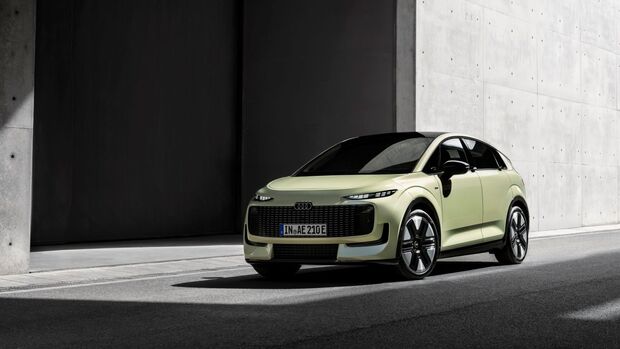 Hellgrüner Audi A2 e-tron in schräger Frontansicht vor moderner Betonarchitektur.