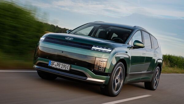 Hyundai Ioniq 9 Elektro-SUV in Gruen bei Fahrt auf Landstrasse aus Front-Seiten-Perspektive