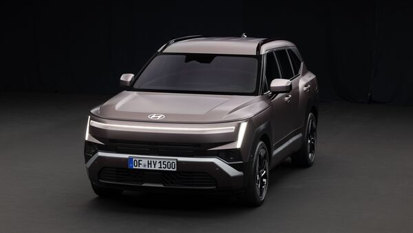 Hyundai Tucson SUV in Grau, aufgenommen schräg von vorne im Studio, mit beleuchtetem LED-Lichtband und vertikalen Tagfahrleuchten.