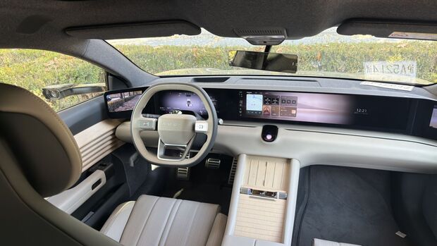 Innenraum des Audi E5 mit Lenkrad, digitalem Kombiinstrument und breitem Displayband ueber das Armaturenbrett.