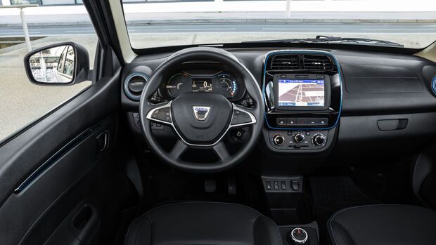 Innenraum des Dacia Spring: Cockpit mit Lenkrad, Instrumentenanzeige und zentralem Display in der Mittelkonsole.