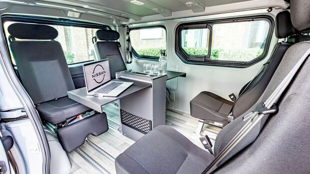 Innenraum des Nissan Primastar FlexVan im Konferenzmodus mit Tisch und drehbaren Sitzen.