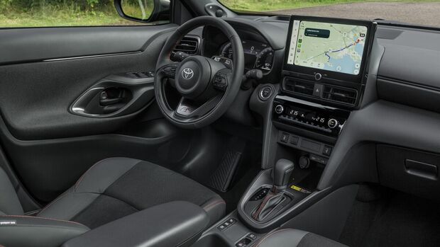 Innenraum des Toyota Yaris Cross Hybrid 130 GR Sport mit Multifunktionslenkrad, digitalem Kombiinstrument, Touchscreen und Mittelkonsole.